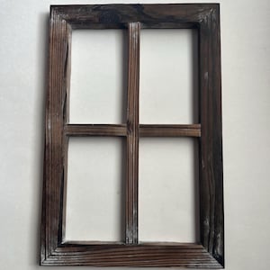 May include: A rectangular, dark brown wooden frame with four window panes. The wood grain is visible, and the frame has a rustic, weathered appearance. The frame is empty, with a white background visible through the panes.