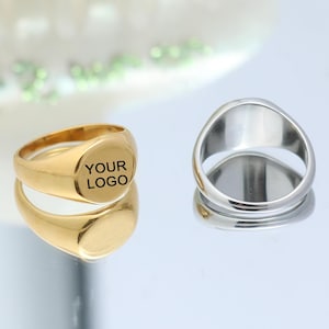 May include: Two signet rings, one gold and one silver. The gold ring has the text "YOUR LOGO" engraved on the top.