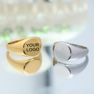 以下が含まれることがあります： 金と銀の2つのシグネットリング。金のリングには、トップに「YOUR LOGO」という文字が刻まれています。
