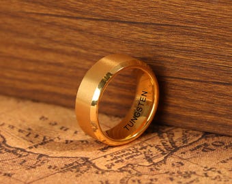 May include: A gold-colored tungsten ring with a brushed finish. The ring has a beveled edge and the word "TUNGSTEN" is engraved on the inside. The ring is displayed on a map.