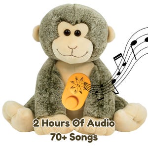 May include: A plush monkey toy in shades of gray and beige, with a smiling face and dark eyes. An orange audio player is attached to the monkey's chest, with musical notes in the background. Text on the image reads "2 Hours Of Audio 70+ Songs."