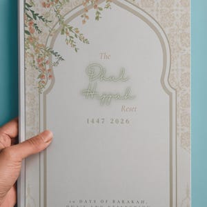 Op de afbeelding: Een softcover journal getiteld "The Dhul Hijjah Reset" met bloemaccenten en een boogvormig ontwerp. De omslag bevat de jaren 1447-2026 en de tekst "10 Days of Barakah, Dua's and Reflection". Het tijdschrift wordt tegen een turquoise achtergrond gehouden.