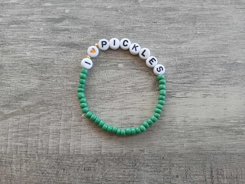 May include: Green beaded bracelet with white beads that spell out "I love pickles".