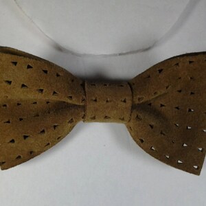 May include: A brown leather bow tie with a triangular cut-out pattern.
