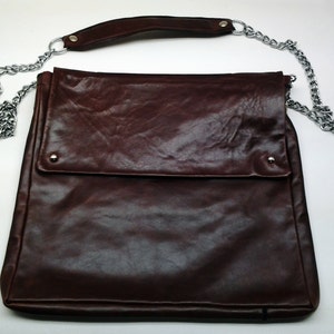 May include: A brown leather shoulder bag with a flap closure and a silver chain strap.