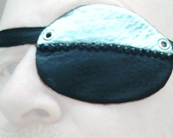 Eye Patch in Black leather and Hand Painted Metallic Silver Leather. Black Rhinestones. Black Elastic Strap. Comfortable Neoprene Lining.
