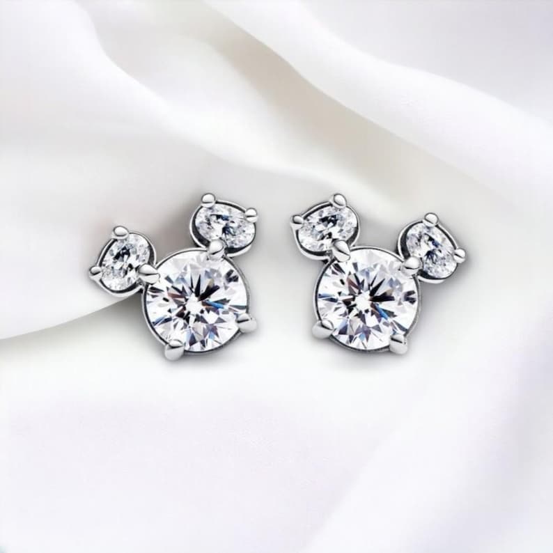 May include: A pair of silver stud earrings featuring a Mickey Mouse design with clear cubic zirconia stones.