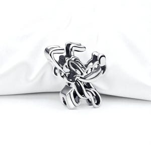 May include: A silver-colored charm featuring a stylized depiction of the Disney character Goofy. The charm is detailed with visible facial features and a curved design, set against a white background.
