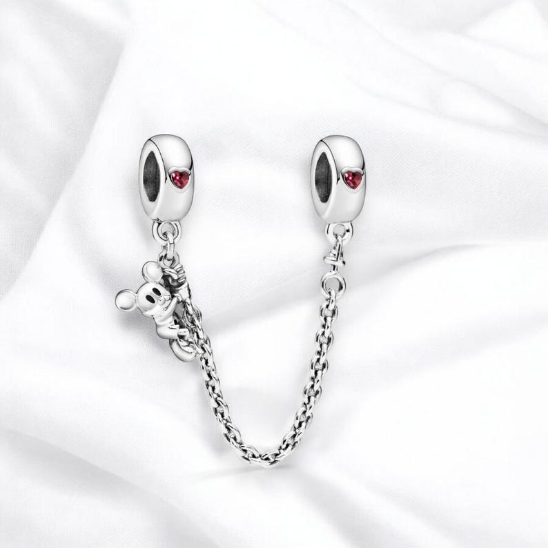 May include: Silver charm bracelet extender with a Mickey Mouse charm and two red heart charms.