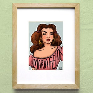Pu&ograve; includere: Un'illustrazione incorniciata di una donna con i capelli castano scuro, che indossa una maglia rosa con la scritta "MARIA FELIX" stampata su di essa. L'illustrazione &egrave; su uno sfondo blu chiaro.
