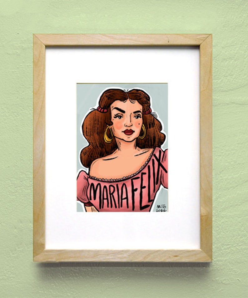 Pu&ograve; includere: Un'illustrazione incorniciata di una donna con i capelli castano scuro, che indossa una maglia rosa con la scritta "MARIA FELIX" stampata su di essa. L'illustrazione &egrave; su uno sfondo blu chiaro.