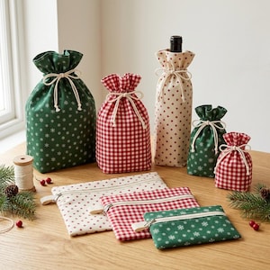 Pode incluir: Uma coleção de bolsas de tecido com cordão e estojos com zíper com padrões de xadrez vermelho e branco, verde com flocos de neve brancos e creme com estrelas vermelhas. Uma bolsa alta contém uma garrafa. Os itens estão sobre uma superfície de madeira.