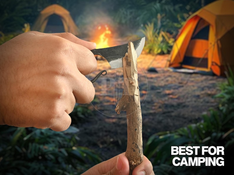 May include: A black camping knife is used to carve a wooden stick. The knife has a curved handle and a sharp blade. The text "BEST FOR CAMPING" is visible in the lower right corner. The background includes tents and a campfire.