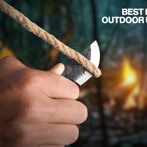 May include: A close-up of a hand holding a small, sharp knife against a rope. The knife has a dark, textured blade and a light-colored handle. The rope is thick and tan. Text in the image reads "BEST FOR OUTDOOR USE."