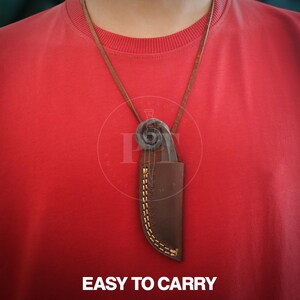May include: A brown leather sheath with a knife and a decorative metal piece is suspended from a brown leather cord. The sheath is stitched with yellow thread. The text "EASY TO CARRY" is at the bottom of the image.