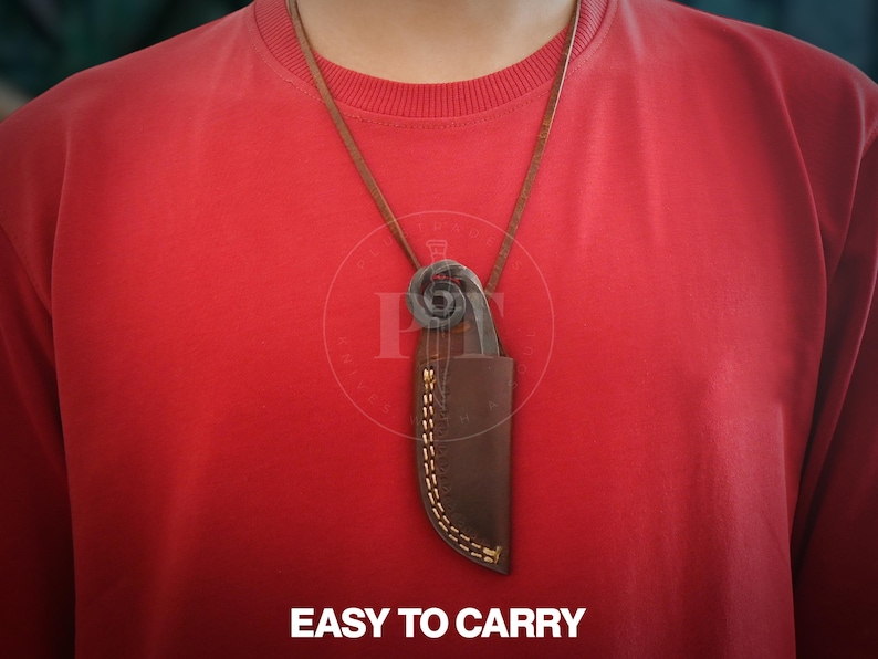 May include: A brown leather sheath with a knife and a decorative metal piece is suspended from a brown leather cord. The sheath is stitched with yellow thread. The text "EASY TO CARRY" is at the bottom of the image.