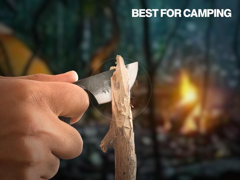 May include: A knife carving wood, with the text "BEST FOR CAMPING" in white. The knife has a dark blade and is cutting a piece of wood. The background is blurred, suggesting a camping scene.