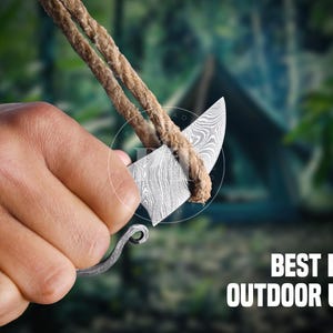 May include: A small, patterned knife with a curved blade is held with a rope. The text "BEST FOR OUTDOOR USE" is displayed in white. The knife has a decorative handle and is set against a blurred green background.