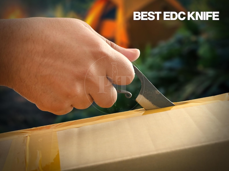 May include: A small, dark-colored EDC knife cutting into a cardboard box. The knife has a curved blade and a loop at the end of the handle. The text "BEST EDC KNIFE" is visible in the upper right corner.