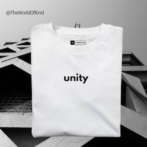 Könnte beinhalten: Weißes T-Shirt mit dem Text "unity" in Schwarz auf der Vorderseite. Das Shirt hat einen Rundhalsausschnitt und kurze Ärmel. Der Markenname "The World of Kind" ist auf einem kleinen Etikett auf der Vorderseite des Shirts aufgedruckt.