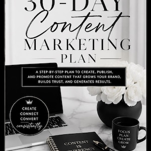 Könnte beinhalten: Ein 30-Tage-Content-Marketing-Plan von Vanity Co. mit einem schwarzen Spiralnotizbuch mit dem Text Content Is Currency, einem schwarzen Stift, einer schwarzen Tasse mit dem Text Focus Plan Create Grow und einem Laptop auf weißem Marmor.