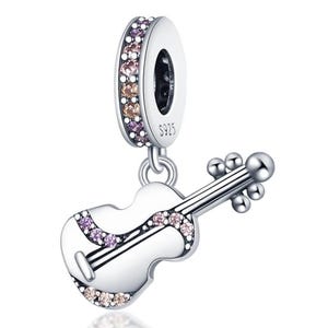 Puede incluir: Un charm de plata con un colgante de viol&iacute;n. El charm presenta un anillo adornado con peque&ntilde;as piedras preciosas de colores. El colgante de viol&iacute;n es blanco con detalles negros y piedras preciosas adicionales. El charm est&aacute; marcado con "S925".