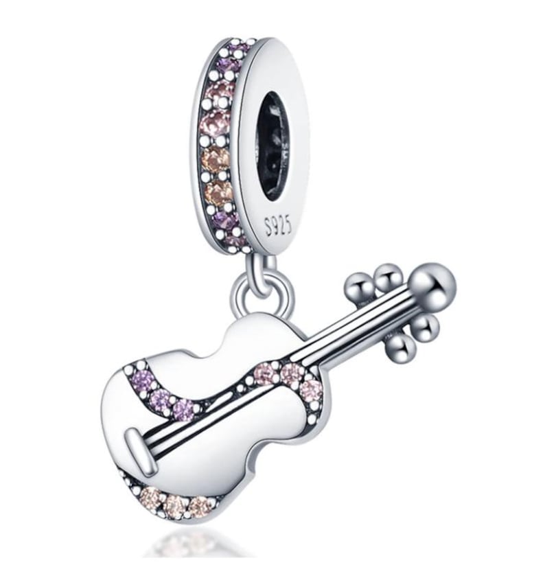 Puede incluir: Un charm de plata con un colgante de viol&iacute;n. El charm presenta un anillo adornado con peque&ntilde;as piedras preciosas de colores. El colgante de viol&iacute;n es blanco con detalles negros y piedras preciosas adicionales. El charm est&aacute; marcado con "S925".