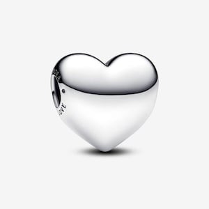 May include: A polished silver heart-shaped charm with a smooth, reflective surface. The charm has a small hole for threading and the word "LOVE" is engraved on the side. The charm is designed to be a pendant or bead.