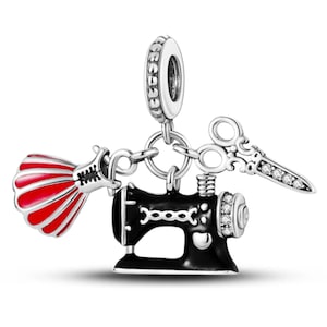 Può includere: Un charm in argento con una macchina da cucire nera, un vestito rosso e bianco e forbici decorate con pietre preziose trasparenti. Il charm è progettato per essere appeso a un braccialetto o una collana, con un tema di cucito e moda.
