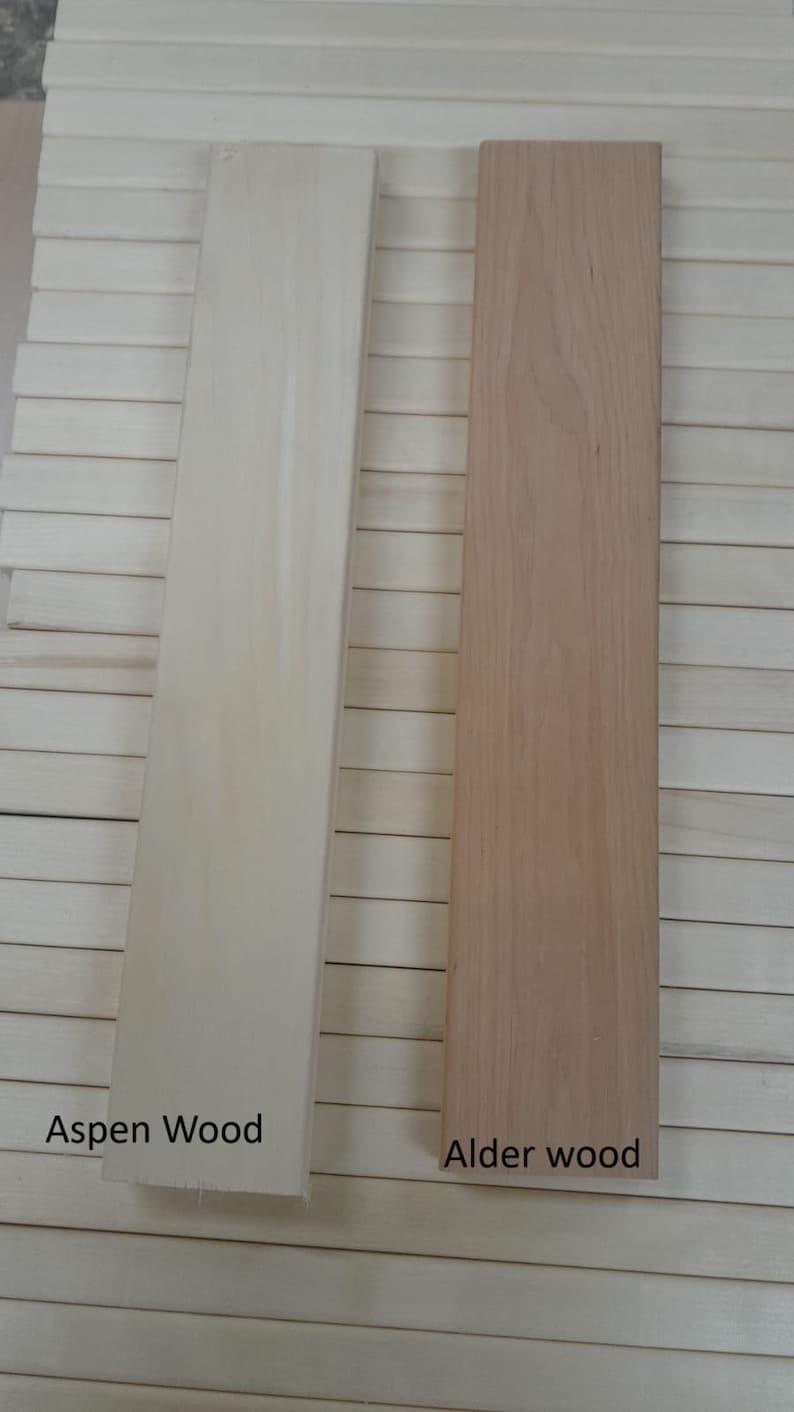May include: Two rectangular wooden planks, one light beige labelled "Aspen Wood" and the other light brown labelled "Alder wood". The planks are displayed against a background of similar wooden slats.