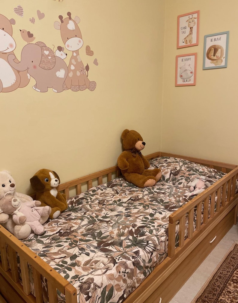 May include: A child's bedroom with a wooden bed, floral bedding, and soft toys. The walls are adorned with animal decals and framed prints with motivational phrases, creating a playful and comforting environment.