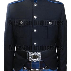 Pode incluir: Casaco militar azul marinho com debrum azul, botões prateados e cinto preto com fivela prateada. O casaco é combinado com um kilt xadrez azul e preto e um sporran branco.