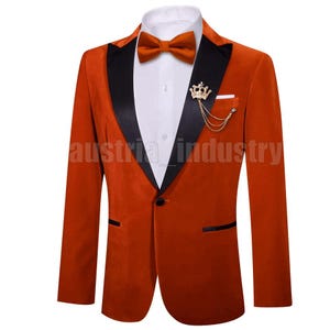 May include: A burnt orange velvet blazer with black lapels, a matching bow tie, and a gold crown pin. The blazer has a white dress shirt underneath and a pocket square. The text "austria industry" is visible.