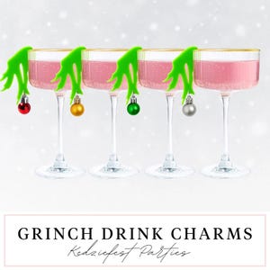 Puede incluir: Cuatro copas de cóctel transparentes con bordes dorados, llenas de líquido rosa, están adornadas con amuletos verdes con temática de Grinch y adornos en miniatura. El texto "GRINCH DRINK CHARMS" se muestra debajo.