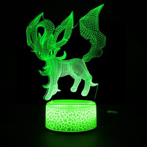 Puede incluir: Una luz nocturna verde impresa en 3D que presenta una criatura estilizada con orejas grandes y una cola larga. La luz tiene un diseño de estructura de alambre y se asienta sobre una base redonda con un patrón agrietado, todo iluminado con un brillo verde brillante.