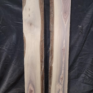 May include: Two unfinished wood slabs with natural edges. The wood grain features light tan, purple, and brown hues. The slabs are rectangular and appear ready for woodworking projects or crafts.