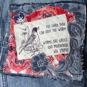 May include: A denim jacket with a decorative patch. The patch features a bird illustration and the text "THE EARLY BIRD CAN HAVE THE WORM WORMS ARE GROSS AND MORNINGS ARE STUPID". The patch has red, white, and blue floral patterns.