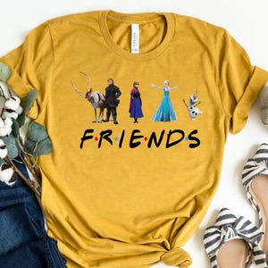 May include: A mustard yellow t-shirt with a graphic of characters from the movie Frozen. The text "FRIENDS" is printed below the graphic.