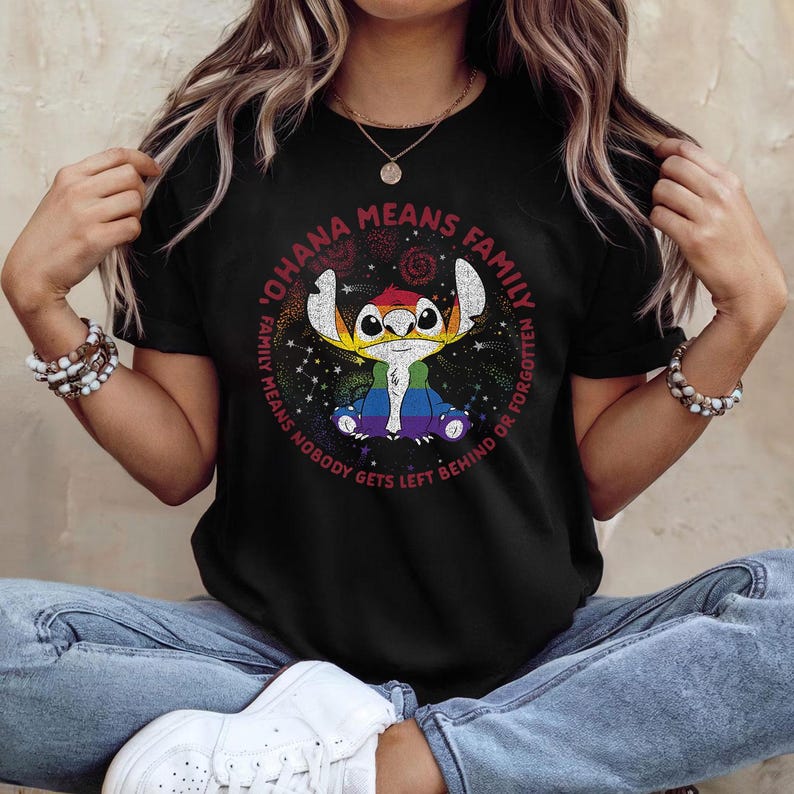 May include: Black t-shirt with a cartoon character in rainbow colours, surrounded by the text "OHANA MEANS FAMILY, NOBODY GETS LEFT BEHIND OR FORGOTTEN" in a circular design. The design is colourful.