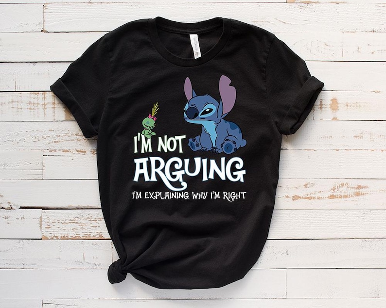 May include: Black t-shirt featuring a blue cartoon character and a green alien. The text "I'M NOT ARGUING I'M EXPLAINING WHY I'M RIGHT" is printed in white. The shirt is made of a soft material.