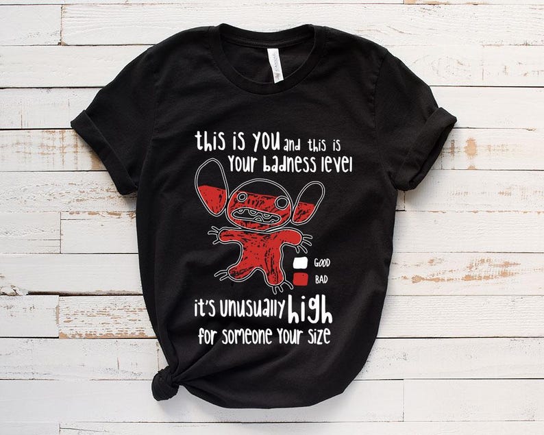 May include: Black t-shirt with a red cartoon character and the text "this is you and this is your badness level. It's unusually high for someone your size." The character has a red body and white eyes. There is a scale below the character with the words "good" and "bad" next to it.