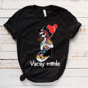 Puede incluir: Camiseta negra con un gr&aacute;fico de un personaje de dibujos animados que lleva un sombrero de Mickey Mouse y sostiene un globo rojo. El texto "Vacay mode" est&aacute; impreso debajo del personaje.
