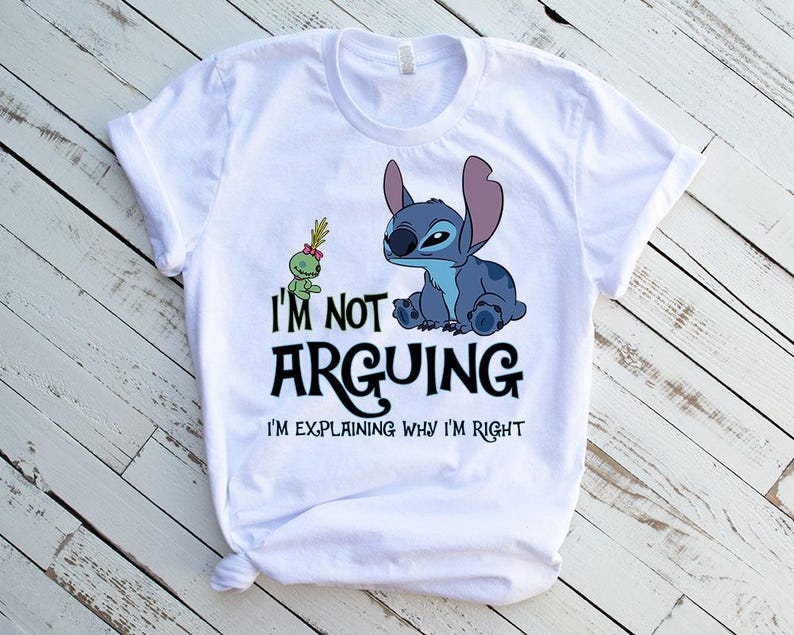 May include: White t-shirt featuring a blue cartoon character and a green alien. The text on the shirt reads "I'M NOT ARGUING I'M EXPLAINING WHY I'M RIGHT". The design is printed on a white t-shirt.