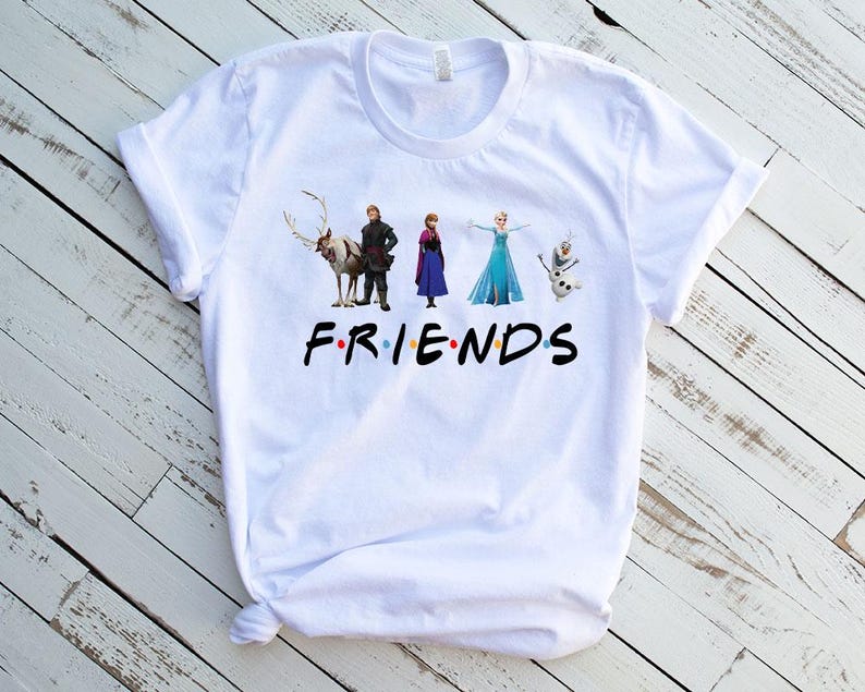 May include: White t-shirt with a graphic of characters from the movie Frozen. The characters are standing in a line and the text "FRIENDS" is below them.