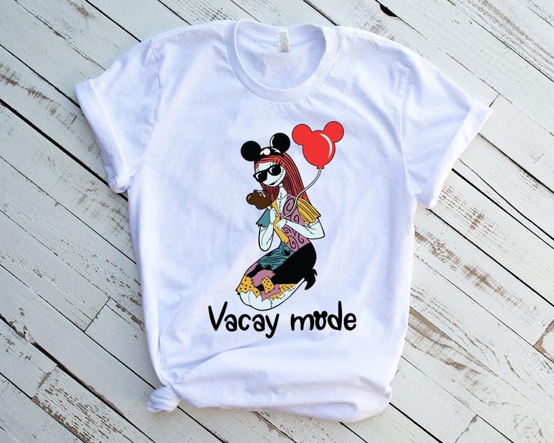 Puede incluir: Camiseta blanca con una imagen de dibujos animados de un personaje con un sombrero de Mickey Mouse y sosteniendo un globo rojo. El texto "Vacay mode" est&aacute; impreso debajo de la imagen.