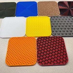 May include: Nine different square-shaped silicone pot holders with various geometric patterns. The patterns include concentric circles, a honeycomb design, a grid of triangles, and a spiral design. The colors include blue, yellow, orange, red, white, gray, and green.