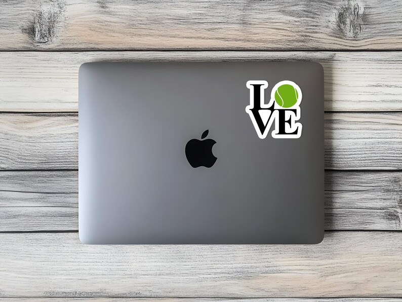 May include: A silver laptop computer with a black Apple logo and a sticker that says "LOVE" with a green tennis ball in the "O".