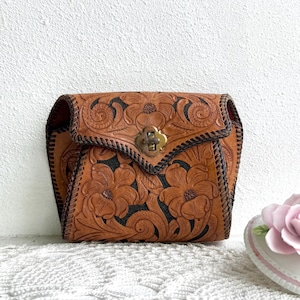 May include: A white ceramic mug with a black handle and the text "But First, Coffee" in a bold, black font. The mug is set against a blurred background, suggesting a cozy setting.