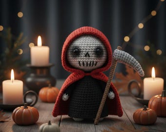 May include: A crocheted Grim Reaper doll with a red hooded cloak and a scythe, set on a wooden surface with pumpkins and lit candles. The doll has a skull face and is dressed in black. The scene evokes a Halloween theme.