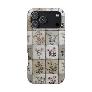 May include: A phone case featuring a floral tile design. The case is covered in a pattern of small, square tiles, each displaying a different watercolor-style flower arrangement in shades of pink, white, and green against a neutral background. The case has a camera cutout.